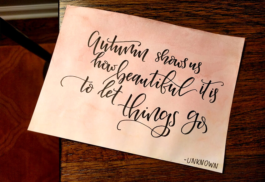 Watercolor card with the saying 'Autumn shows us how beautiful it is to let things go' hand-calligraphied.